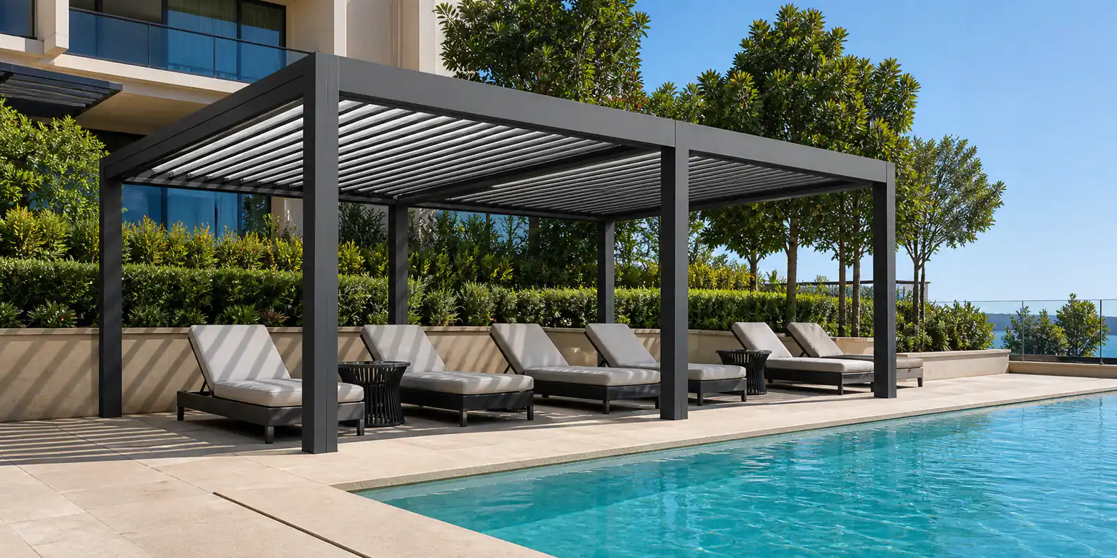 Motorized louvered pergola shading loungers beside a hotel swimming pool